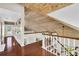 Hallway with wood floors, wooden plank ceiling, white railing, stairs and a door to a deck at 38 Seawatch Lake Dr, Boca Grande, FL 33921