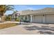 Attractive home featuring a three-car garage and manicured landscaping with palm trees along the paved driveway at 4 Sportsman Ln, Rotonda West, FL 33947