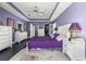 This main bedroom features purple walls, tray ceilings, and an ensuite bathroom with walk-in closet at 4 Sportsman Ln, Rotonda West, FL 33947