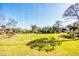 Expansive backyard featuring lush green lawn and mature trees, viewed through lanai screen at 4260 Placida Rd # 8D, Englewood, FL 34224