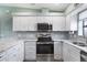 Stylish kitchen featuring stainless steel appliances, granite countertops, and white cabinets at 4260 Placida Rd # 8D, Englewood, FL 34224