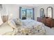 Bright bedroom featuring a large window, dresser, and a comfortable queen-sized bed with floral patterned linens at 6610 Gasparilla Pines Blvd # 113, Englewood, FL 34224