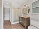 Bathroom featuring wood-look tile floors, updated vanity with round mirror, and a glass-enclosed shower at 730 Buckskin Ct, Englewood, FL 34223