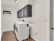 Functional laundry room with wood-look flooring, overhead cabinets, and modern washer and dryer units at 730 Buckskin Ct, Englewood, FL 34223