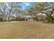 View of the detached garage and circular driveway, surrounded by mature trees and lush greenery at 746 Brentwood Dr, Venice, FL 34292