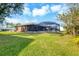 Backyard view featuring a screened pool enclosure and well-kept lawn with mature trees at 9260 Saint Catherine Ave, Englewood, FL 34224