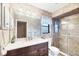 Tastefully designed bathroom with a dark wood vanity, patterned wallpaper, and tiled shower at 9260 Saint Catherine Ave, Englewood, FL 34224