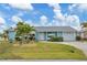 Inviting curb appeal with lush lawn, tropical landscaping, and a bright, cheerful exterior paint at 9382 Rosebud Cir, Port Charlotte, FL 33981