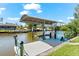 Covered boat dock on a sunny day featuring a boat lift with adjacent waterways and residential properties at 10491 Sarasota Rd, Port Charlotte, FL 33981