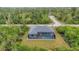 Aerial view showcases a modern home with a screened-in pool surrounded by lush greenery and trees at 10782 Kearsarge Cir, Port Charlotte, FL 33981