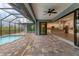 Beautiful lanai with stone flooring and ceiling fan showcasing the pool and open concept access to the kitchen at 10782 Kearsarge Cir, Port Charlotte, FL 33981