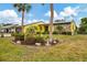 Yellow home with stone facade and meticulously landscaped yard including palm trees at 1173 Brown St, Englewood, FL 34224