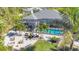 An aerial view displays a home with a screened-in pool area, set in a neighborhood with lush greenery at 13379 Journal Ln, Port Charlotte, FL 33981