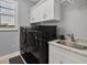 Modern laundry room with front load washer and dryer and overhead storage cabinets at 14286 Fort Worth Cir, Port Charlotte, FL 33981