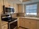 Well-equipped kitchen featuring stainless steel appliances and cream colored cabinets at 150 Englewood Isles Pkwy # 201, Englewood, FL 34223
