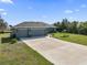 Home boasts a spacious three-car garage and long driveway complemented by a landscaped yard and inviting front entrance at 15251 Appleton Blvd, Port Charlotte, FL 33981