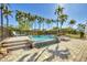 Inviting backyard pool featuring a cascading waterfall, bordered by lush palm trees and brick pavers at 16251 Sunset Pines Cir, Boca Grande, FL 33921