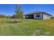 Spacious backyard featuring lush green grass, a young tree, and a peaceful screened patio in a serene setting at 1758 Saddlewood Cir, Port Charlotte, FL 33953