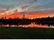 Tranquil sunset reflecting on the lake beyond the green lawn, adding a touch of serenity to the property at 1758 Saddlewood Cir, Port Charlotte, FL 33953