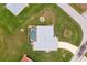 An aerial view of a home with a screened pool, driveway, luscious lawn, mature palm tree, and fire pit at 2 Bunker Way, Rotonda West, FL 33947