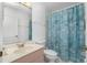 Well-lit bathroom showcasing tiled shower with seashell curtain, white toilet, and marble countertop sink at 2 Bunker Way, Rotonda West, FL 33947