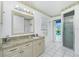 Light-filled bathroom with granite vanity, white tile flooring and shower with exterior pool access at 2 Bunker Way, Rotonda West, FL 33947