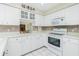 Modern kitchen showcasing white cabinets, tiled backsplash, and white appliances at 2 Bunker Way, Rotonda West, FL 33947