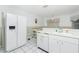 Efficient kitchen layout with white appliances, tiled floors, and bright lighting at 2 Bunker Way, Rotonda West, FL 33947