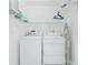 Bright laundry room with white washer, dryer, shelving and an ironing board against the wall at 2 Bunker Way, Rotonda West, FL 33947