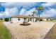 Single story home with white exterior, rock garden, brown roof and palm trees at 20 Bunker Way, Rotonda West, FL 33947