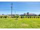 Grassy backyard with room to roam and distant homes beyond the treeline at 213 Sunset Rd, Rotonda West, FL 33947