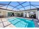 Wide shot of in-ground pool with screened enclosure and travertine tile deck at 213 Sunset Rd, Rotonda West, FL 33947