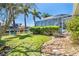 View of the backyard with a green lawn, tropical landscaping, and a view of the canal at 471 Capri Isles Ct, Punta Gorda, FL 33950