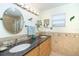 Double sink bathroom vanity with granite counters, decorative mirror, and wall accents at 471 Capri Isles Ct, Punta Gorda, FL 33950
