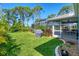 Spacious backyard with lush green grass, mature trees, and a screened-in patio area, perfect for outdoor living at 5 Pine Valley Rd, Rotonda West, FL 33947