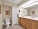 Bright bathroom featuring a double sink vanity, toilet, and a large mirror providing ample lighting at 5 Pine Valley Rd, Rotonda West, FL 33947