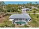 Aerial view of a home with a screened-in pool, lush landscaping, and a serene backyard setting at 5258 Grassland Ter, Port Charlotte, FL 33981