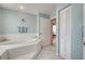 Bright bathroom featuring a soaking tub, tiled floors, and an open doorway at 587 Viridian St, Englewood, FL 34223