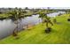 Beautiful waterfront property featuring a private dock and boat lift, enhanced by lush green grass and tropical palm trees at 751 Ellicott Nw Cir, Port Charlotte, FL 33952