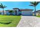 A lovely one-story home features a manicured lawn, brick driveway, and an attached garage at 8144 Antwerp Cir, Port Charlotte, FL 33981