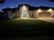 Inviting home exterior with warm lighting, manicured lawn, and palm trees at night at 8144 Antwerp Cir, Port Charlotte, FL 33981