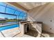 Screened lanai featuring an outdoor kitchen with granite countertops, refrigerator, and a sink overlooking the pool and waterway at 8144 Antwerp Cir, Port Charlotte, FL 33981
