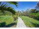 Backyard walkway with lush landscaping, leading to a green lawn area perfect for gardening at 9350 Prospect Ave, Englewood, FL 34224
