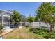 Landscaped backyard with a screened-in lanai, mature trees, and a white picket fence at 10082 Army Cir, Port Charlotte, FL 33981