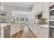 Bright kitchen features wood floors, modern stainless steel appliances, and white cabinets with black hardware at 10082 Army Cir, Port Charlotte, FL 33981