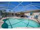 Backyard oasis showcasing the beautiful pool under a screened enclosure and an outdoor seating area for relaxing at 10183 Winding River Rd, Punta Gorda, FL 33950