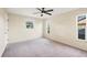 Bright, carpeted bedroom with a ceiling fan and three windows for ample natural light at 10299 Willmington Blvd, Englewood, FL 34224