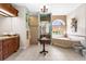 Lovely primary bathroom boasting granite counters, dual sinks, tiled shower, and a soaking tub under an arched window at 103 Mecca St, Port Charlotte, FL 33954