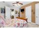 Bright bedroom featuring a floral bedspread, ceiling fan, and a TV, with a glimpse into the kitchen at 103 Mecca St, Port Charlotte, FL 33954