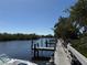 Scenic view of a wooden dock along a canal, surrounded by lush greenery under a clear sky at 107 Jose Gaspar Dr, Englewood, FL 34223